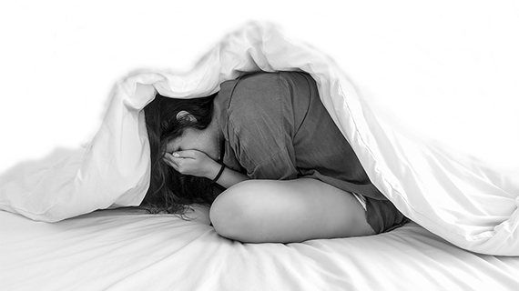 Teenage girl with anxiety hiding under blanket